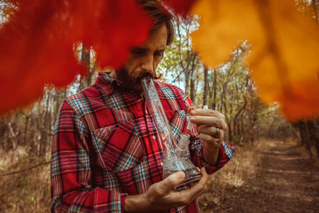 man smoking bong in forest